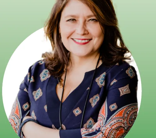 Retrato de Alejandra Sepúlveda, sonriente, de cabello castaño y blusa azul estampada, con los brazos cruzados.